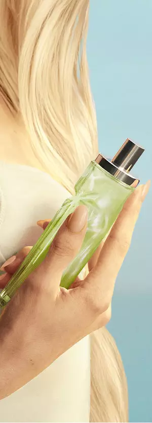 Nouveau Starlicious Pistachio Praline en main mettant en vedette une mannequin aux longs cheveux blonds et aux yeux bleus, vêtue d’une robe jaune pâle et tenant le flacon de la fragrance Pistachio Praline.
