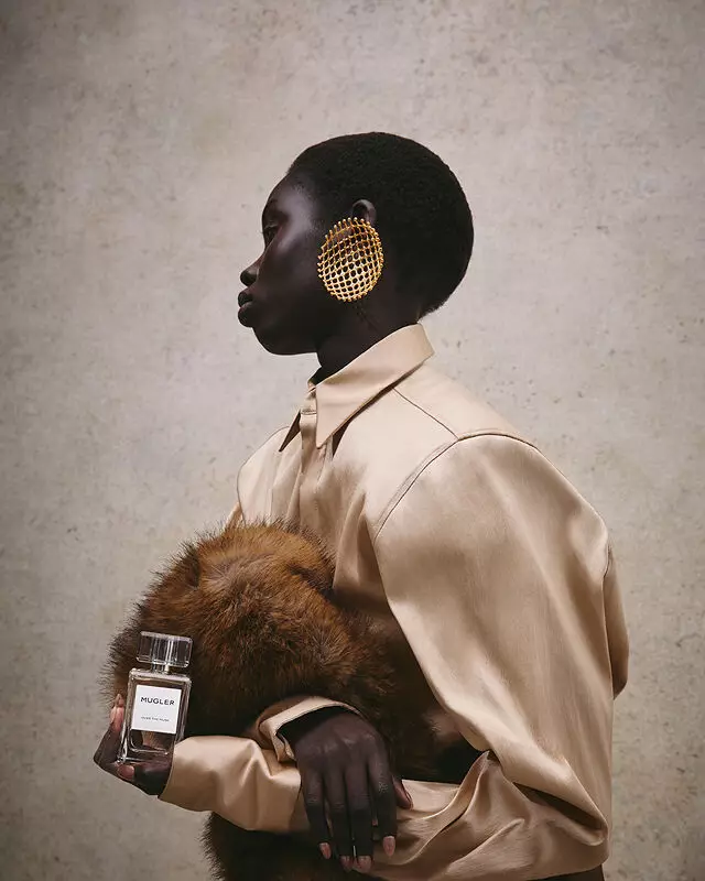 Close-up of a hand holding Mugler Over The Musk fragrance against a luxurious fur background.