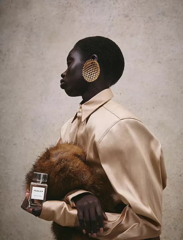 Close-up of a hand holding Mugler Over The Musk fragrance against a luxurious fur background.