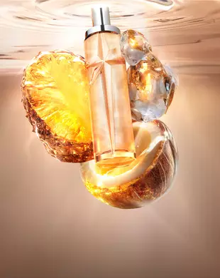 Une nature morte du Nouveau Starlicious Pineapple Musk mettant en vedette le flacon de verre élancé entouré de ses ingrédients clés : une tranche d’ananas lumineuse, une demi-noix de coco ouverte et du musc cristallin, le tout sur fond d’eau ondulante, chaleureuse et lumineuse.